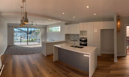 Drummoyne install Modern kitchen and living area with pendant lights, large windows, and a balcony overlooking a marina with boats.