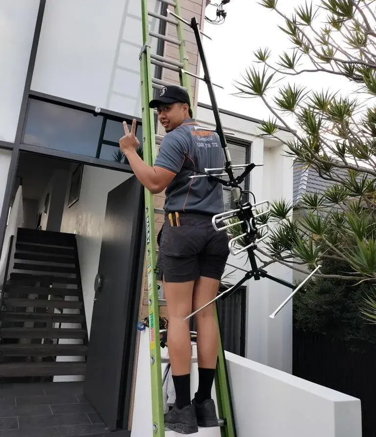 A Professional TV antenna Expert climbing on the ladder with the TV antenna