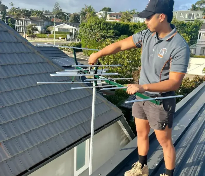 Technician repairing TV antenna mast on a rooftop in Sydney, ensuring optimal digital TV and satellite reception.